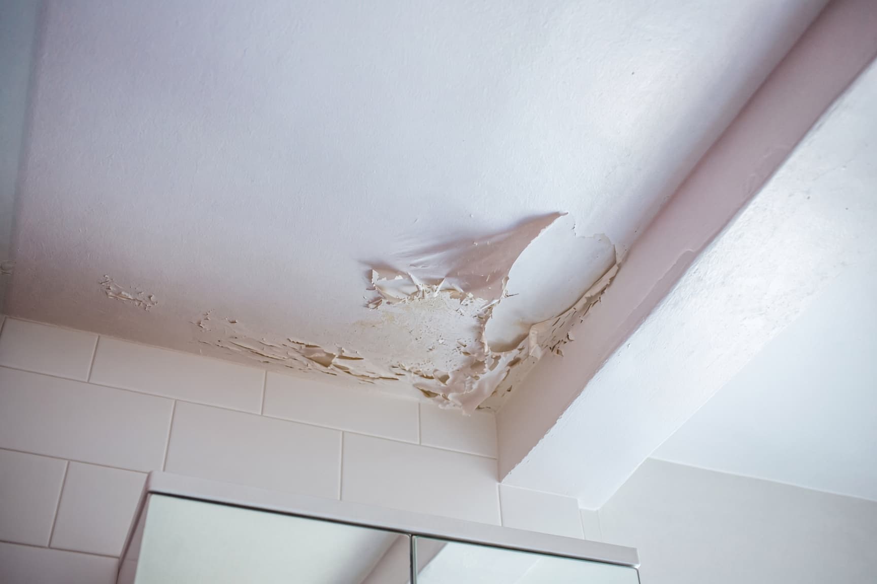 Peeling paint on a bathroom ceiling in San Diego before repair