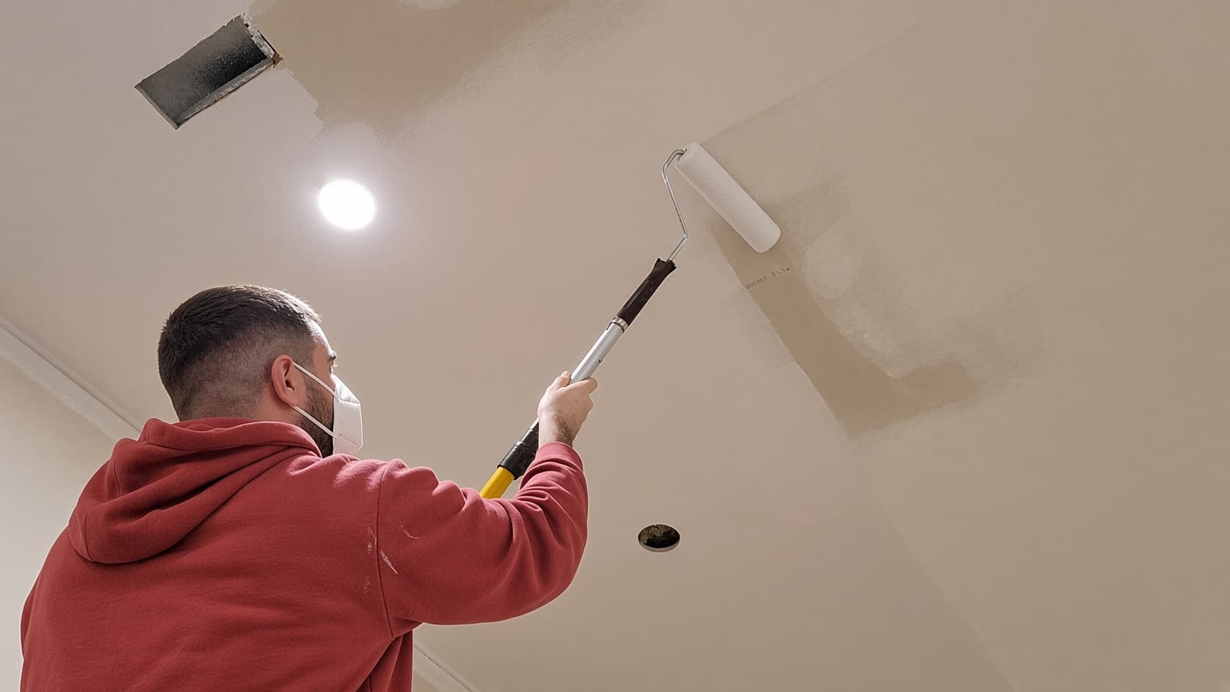 Painter priming a smooth ceiling after popcorn removal in a San Diego home